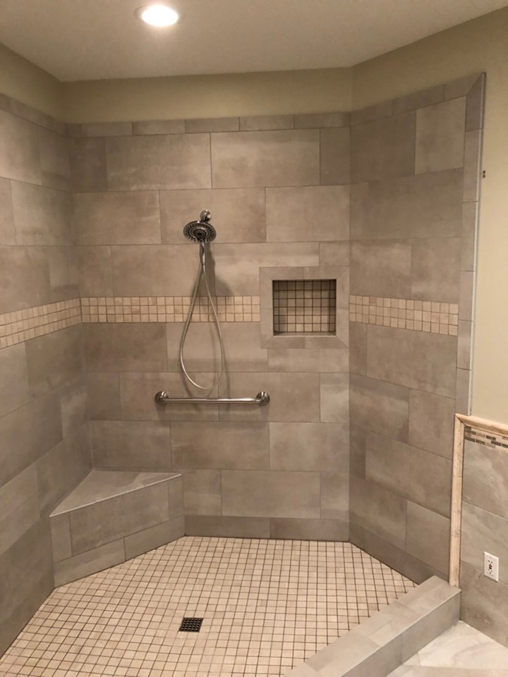 Large custom tiled shower with corner seat, storage niche, handheld fixture, and grab bar