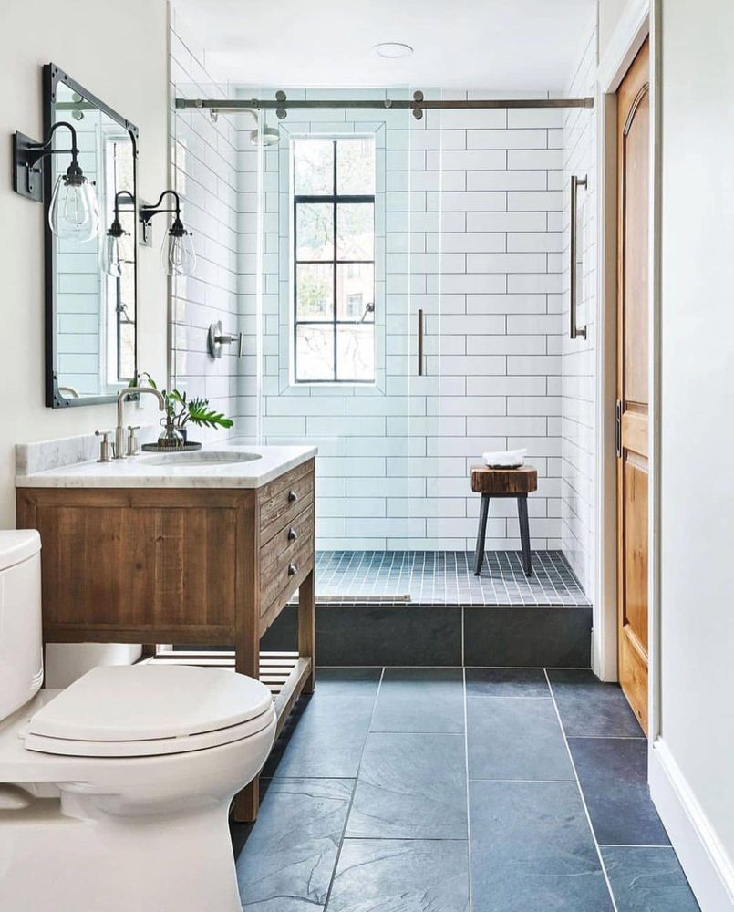 Bright bathroom with white subway tile shower, wood vanity, and blue-gray floor tile