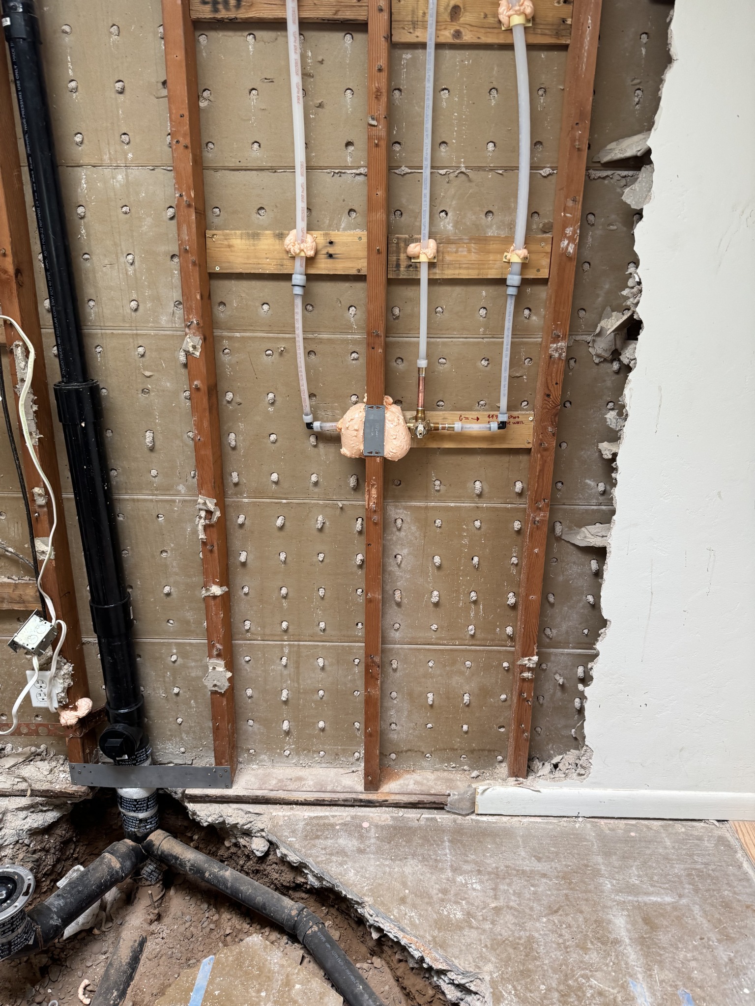 Shower renovation with the wall opened to show updated plumbing and drainage work